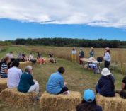 People sit in a half-circle on bales of straw listening to a presentation at the KBS Long-term Ecological Research program site.