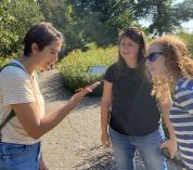 From left: Isabela Borges, Kara Haas, and Robin Waterman observe a monarch butterfly that landed on Isabela's palm.