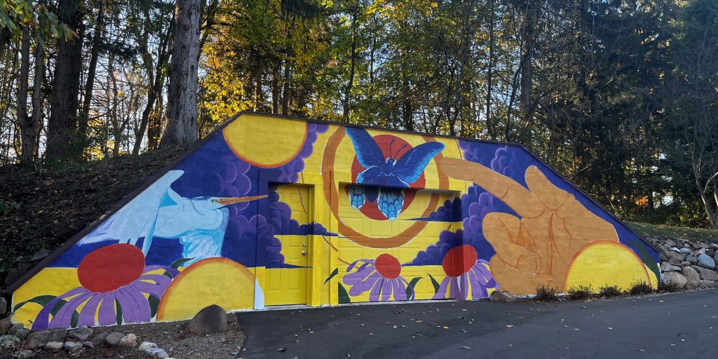 View of the finished mural, titled "Complementary," which features bright colors and images of flowers and butterflies.