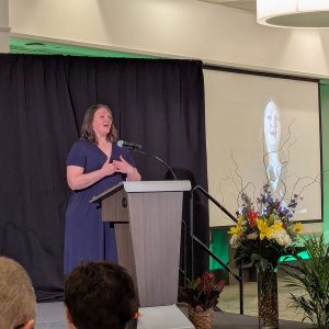 Sarah Reimer speaks from a podium during the ceremony honoring 2024-25 Jack Breslin Distinguished Staff Award recipients.