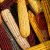 Close up of a bin of dried corn cobs of various colors.