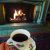 A person holds a cup of tea in an ornate teacup in front of the fireplace in the Manor House living room.