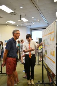 Randall Hatfield explains details on his research poster to faculty member Nick Haddad at the 2025 KBS Undergraduate Research Symposium.