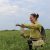 Lauren Sullivan sprinkles seeds in a grassland area.
