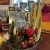 A winter arrangement featuring narcissus bulbs, a miniature evergreen tree, and tree ornaments, sits on a table.