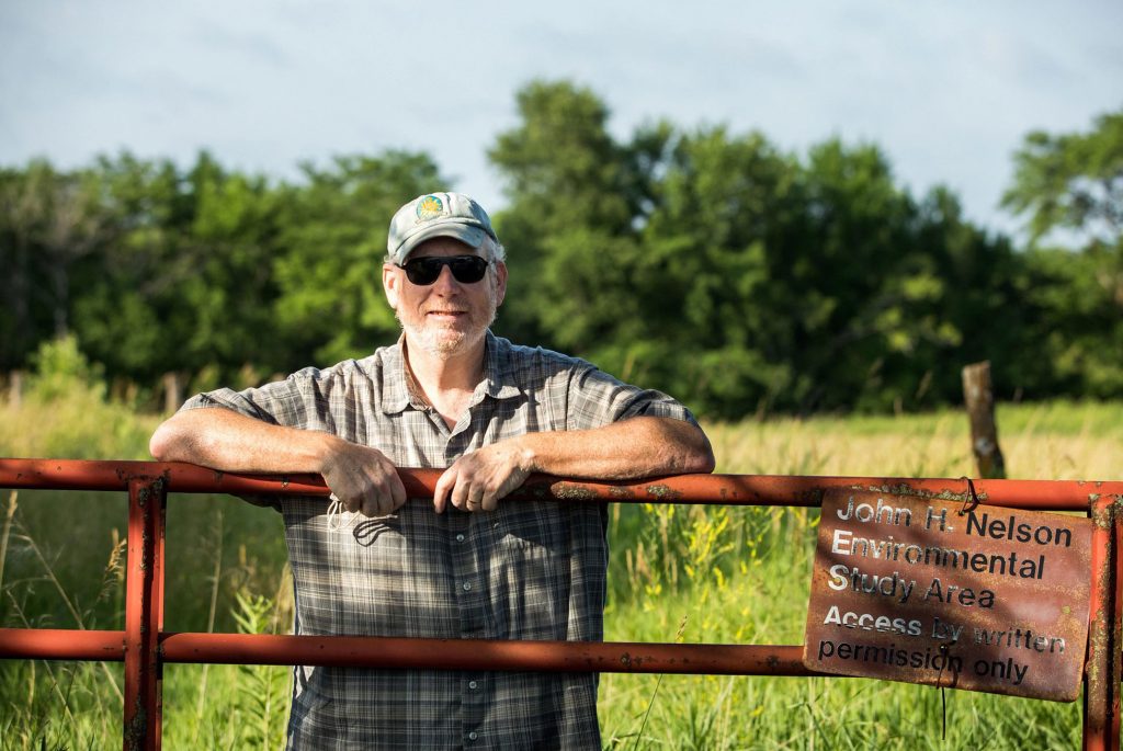 Dr. Bryan Foster leans against a metal gate at the University of Kansas Field Station, where he served as director for several years.