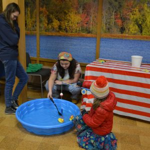 Two teen volunteers help a young attendee fish for a rubber duck in a kiddie pool at a past Ducky Day event at the W.K. Kellogg Bird Sanctuary.