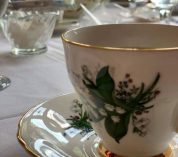 Close-up image of a teacup of a table with a white tablecloth.