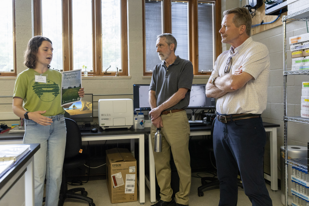 Rachel Drobnak talks about prairie strip research at KBS while Jeff Conner, former interim director of KBS, and Kevin Guskiewicz, MSU president, look on.