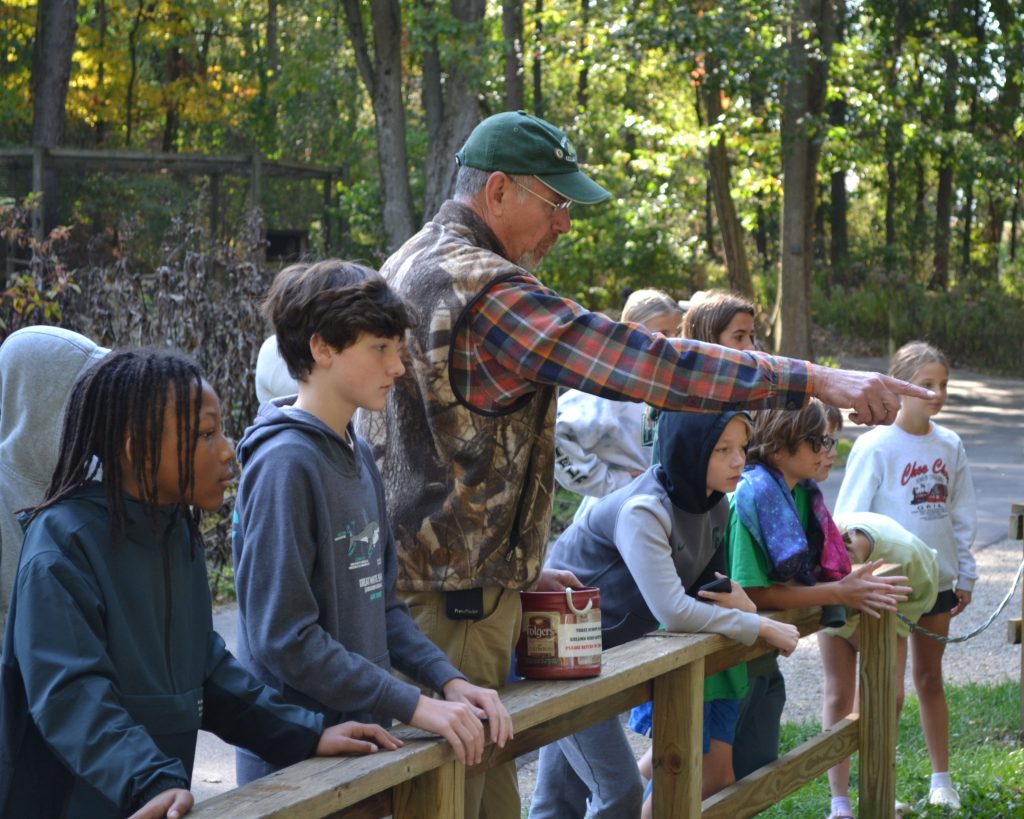 A W.K. Kellogg Bird Sanctuary volunteer points out something interesting to a group of middle school students on a field trip.