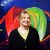 Artist Ellen VanderMyde stands smiling against a green and red background.