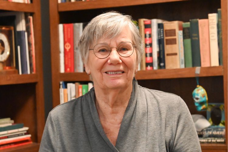 Patricia "Patti" Chipman poses for a photo with shelves filled with books in the background.